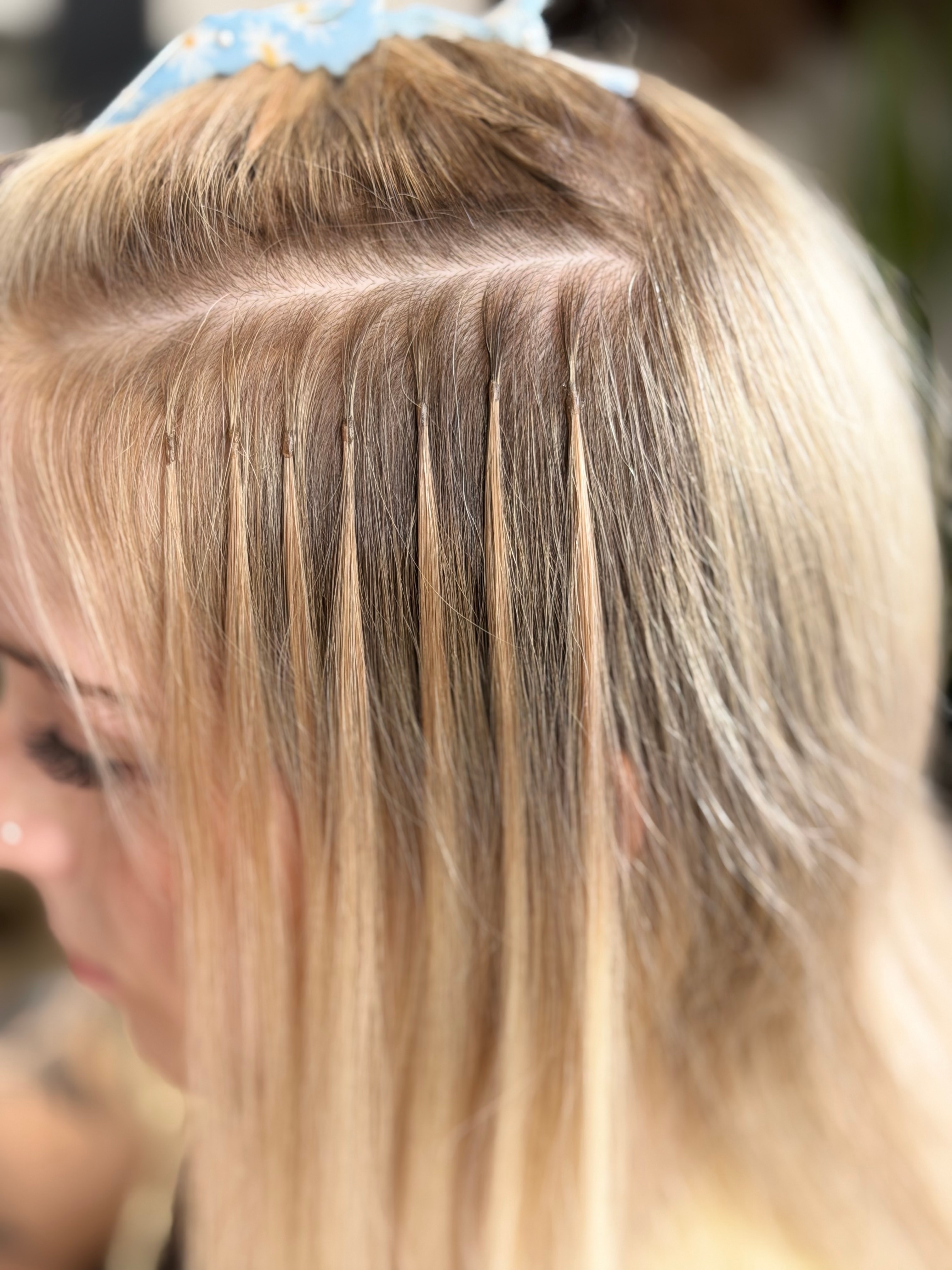 Small keratin bonds visible along a neat parting in blonde hair.